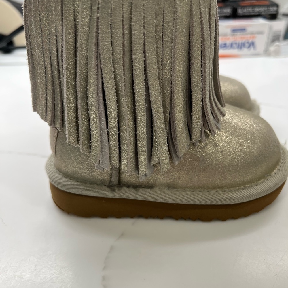 Toddler girl silver UGGs with fringe.